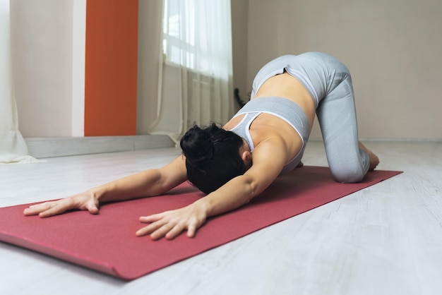 Una mujer practicando yoga realiza una variación del ejercicio balasana la pose de un niño