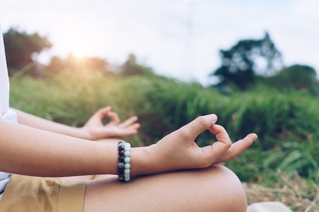 Mujer practicando yoga, respiración, ejercicio de meditación, al aire libre en el campo de hierba. Bienestar, concepto de bienestar