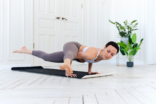 Mujer practicando yoga en su fondo mínimo de la casa blanca