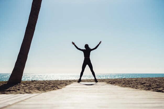 Foto mujer va a practicar deportes en la orilla de la mar mujeres realizan ejercicios deportivos siluetas del cuerpo en