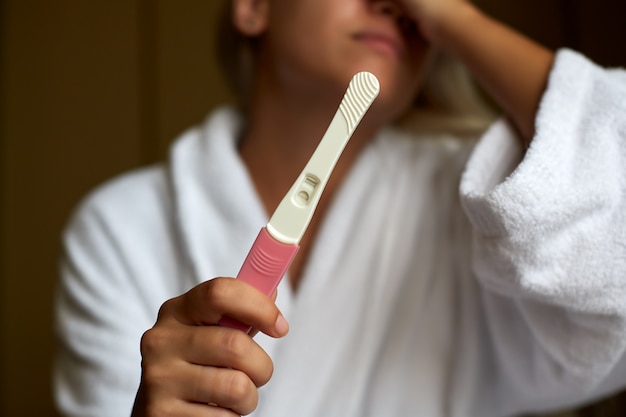 Mujer preocupada en el baño con prueba de embarazo casera