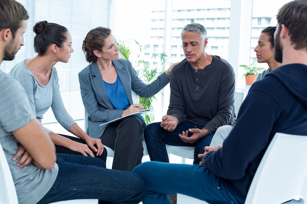 Mujer preocupada consolando a otro en grupo de rehabilitación