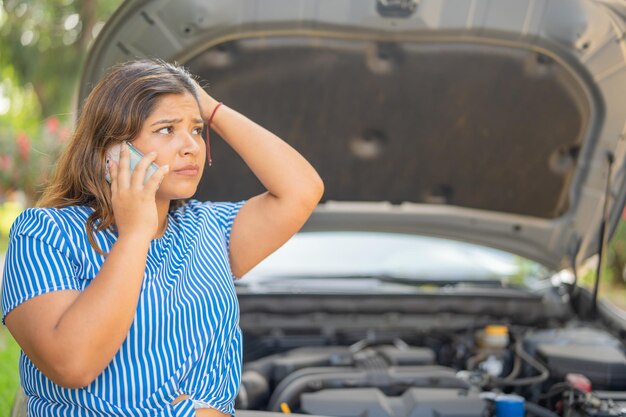 Foto mujer preocupada hablando por teléfono móvil pidiendo ayuda debido a problemas mecánicos