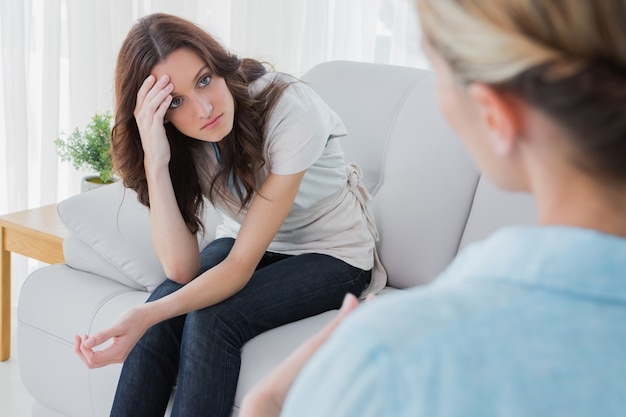 Mujer preocupada sentada y mirando a su terapeuta