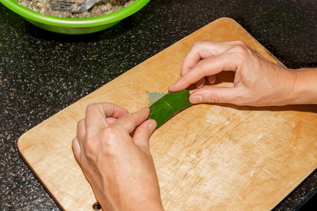 Una mujer prepara la comida en casa La carne picada se envuelve en hojas de parra sobre una tabla de madera dolma