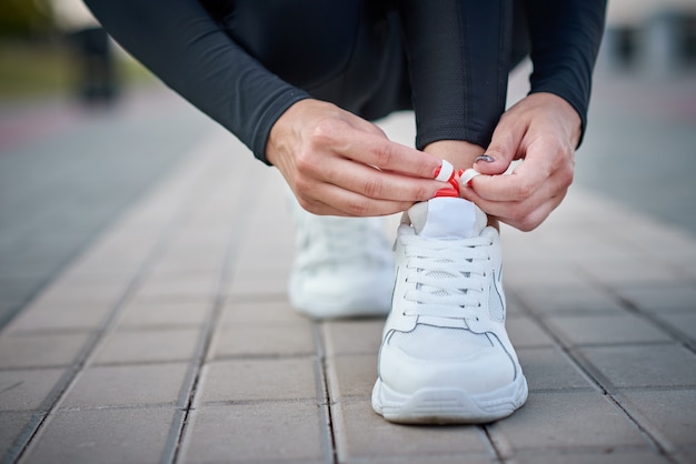 La mujer se prepara para correr. Manos femeninas atar cordones de zapatos en zapatillas deportivas