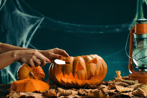 mujer se prepara para Halloween y tallando una persona de calabaza