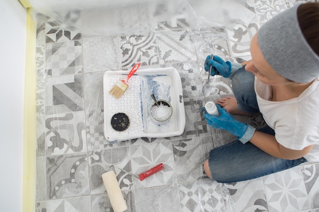 Una mujer prepara pintura para pintar las paredes de la cocina Preparación de herramientas y pinturas para pintar