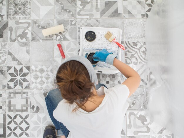 Una mujer prepara pintura para pintar las paredes de la cocina Preparación de herramientas y pinturas para pintar