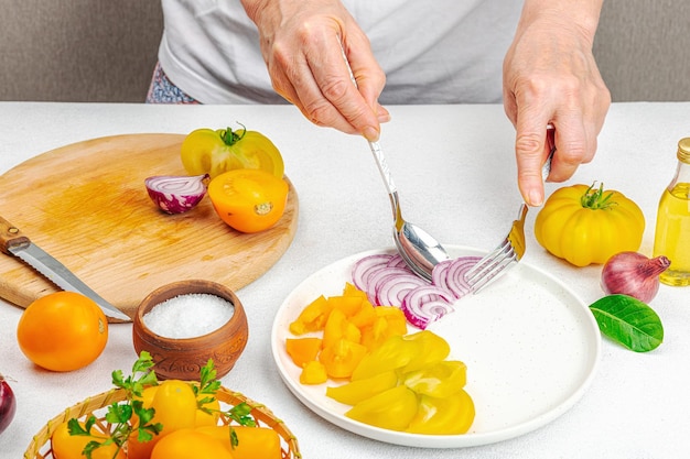 Foto una mujer está preparando una ensalada de tomate verduras maduras hierbas especias aromáticas aceite de oliva cocina casera ingredientes frescos
