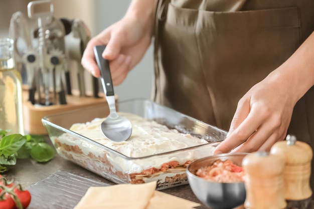 Mujer preparando lasaña de carne en la cocina