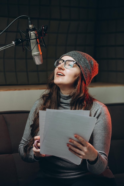 Foto mujer preparando material antes de la grabación del estudio del programa de radio sala insonorizada para la grabación profesional de voces el artista de voz trabaja con material de algún programa de transmisión en vivo doblaje