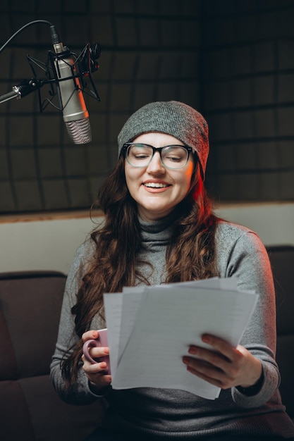 Mujer preparando material antes de la grabación del estudio del programa de radio Sala insonorizada para la grabación profesional de voces El artista de voz trabaja con material de algún programa de transmisión en vivo Doblaje