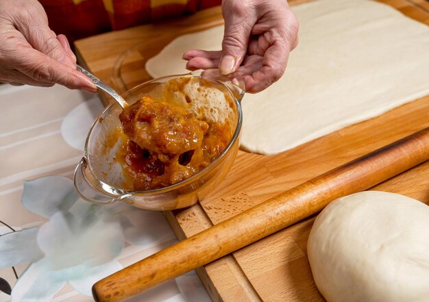 Mujer preparando pastel de rollo dulce con mermelada