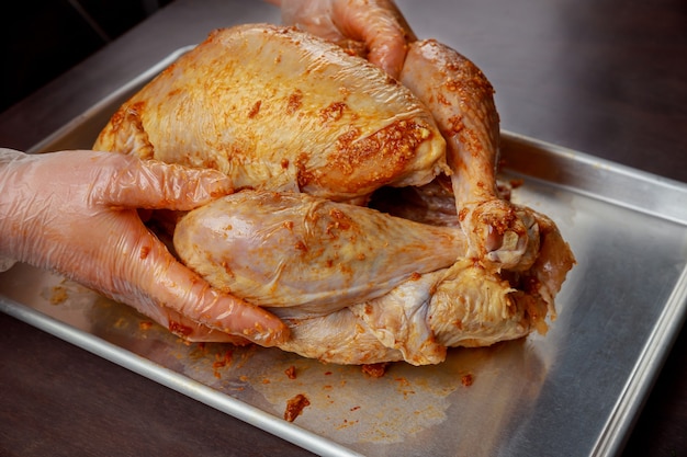 Mujer preparando el pavo de Navidad en una bandeja para hornear.