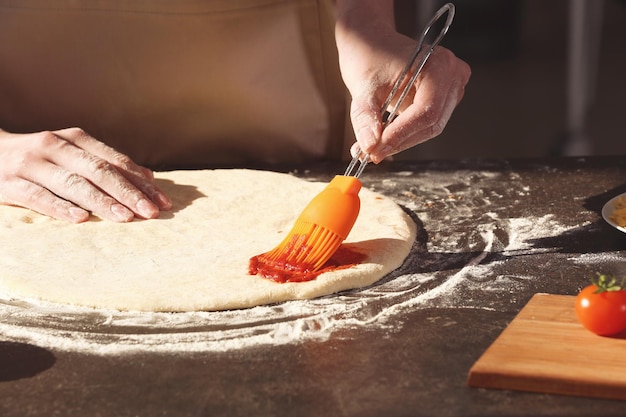 Foto mujer preparando pizza en la mesa de la cocina