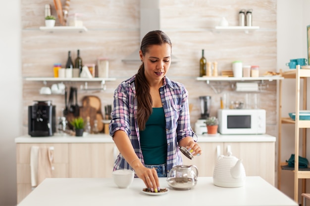 Mujer preparando té verde para el desayuno en la cocina