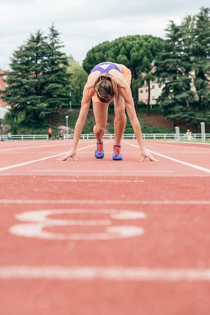 Mujer preparándose para empezar a correr en el estadio