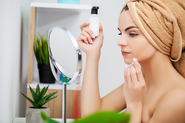 Mujer preparándose para el trabajo haciendo maquillaje por la mañana en el espejo del baño en casa