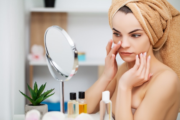 Mujer preparándose para el trabajo haciendo maquillaje por la mañana en el espejo del baño en casa