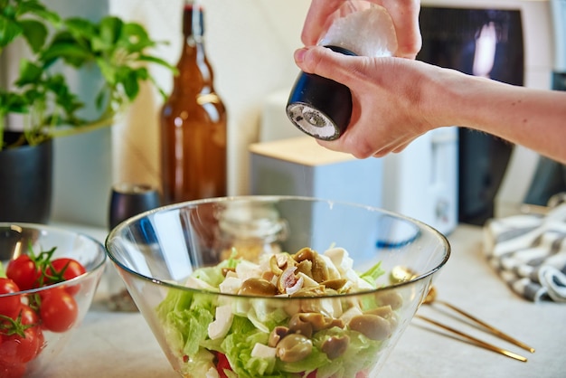 Mujer preparar ensalada de vegetales verdes en un tazón en la cocina