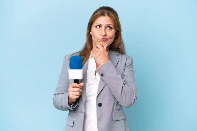 Mujer presentadora de televisión de mediana edad sobre fondo azul aislado que tiene dudas