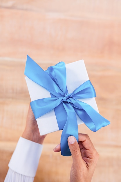 Mujer presentando regalo con cinta azul