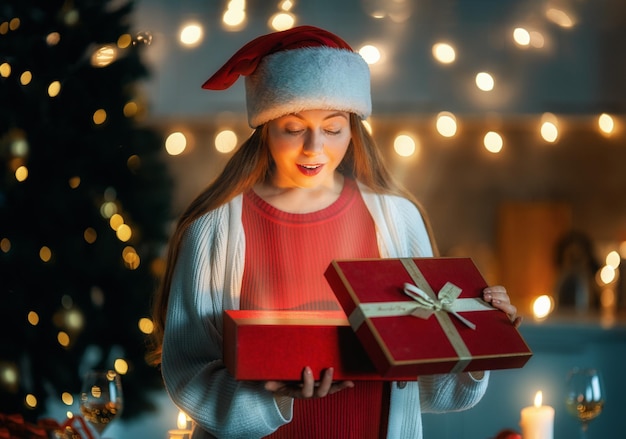 Mujer con presente cerca del árbol de Navidad en el interior