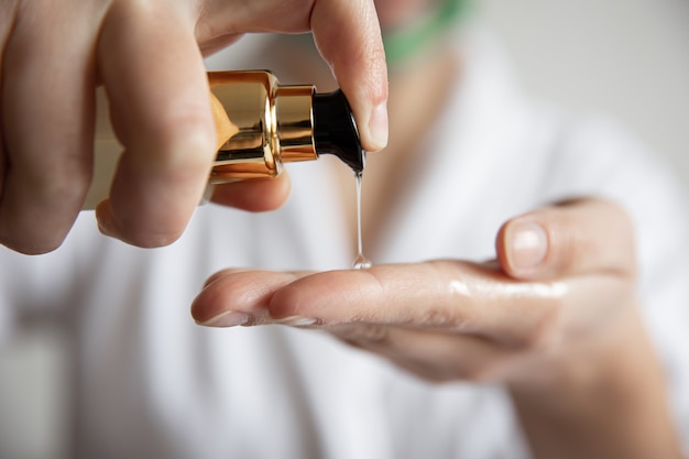 Una mujer presiona sobre el dispensador de productos para el cuidado de la belleza fondo borroso