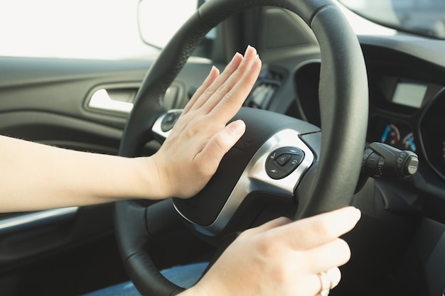 Mujer presionando el botón de bocinazo en el volante