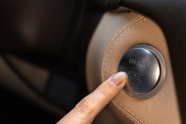 Mujer presionando el botón de inicio y parada del motor en un auto deportivo de lujo vista de primer plano foto