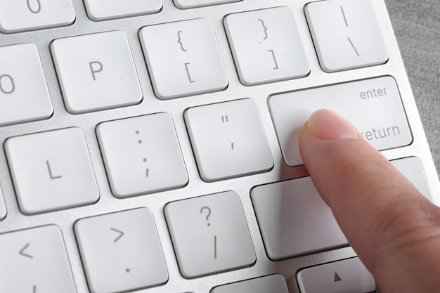 Foto mujer presionando el botón en el teclado de la computadora closeup