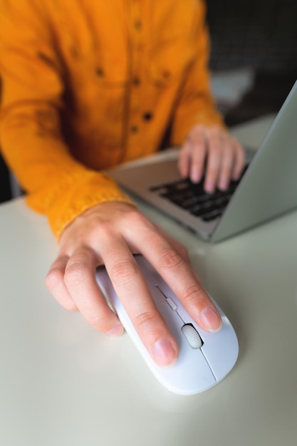 Mujer de primer plano buscando y haciendo clic con el ratón usando una computadora portátil concepto de compras en línea borroso