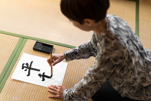 Mujer de primer plano pintando letras japonesas