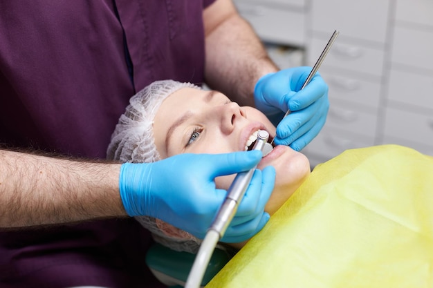 Mujer de primer plano en la silla del dentista Ortodoncista revisando los dientes curando la caries en la clínica de odontología