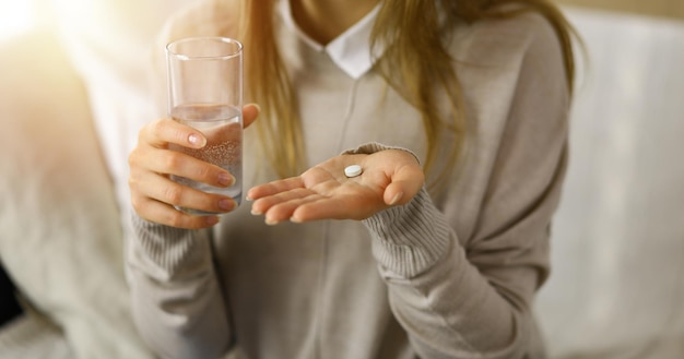 Mujer de primer plano sosteniendo pastillas para tomar medicamentos, curar el dolor de cabeza. Concepto de medicina durante el autoaislamiento y la pandemia de coronavirus