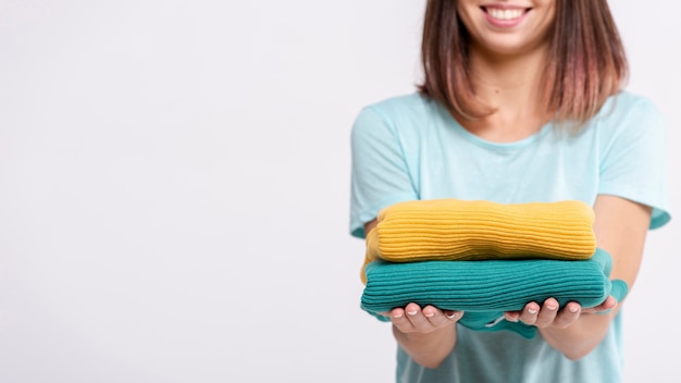 Mujer de primer plano sosteniendo suéteres de colores