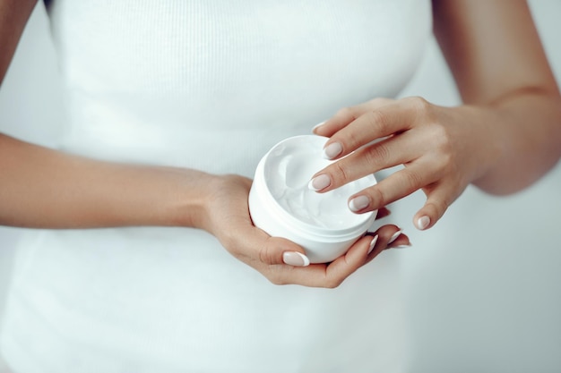 Mujer de primer plano sostiene y aplica crema protectora en las manos Cuidado de la piel de las manos Crema cosmética