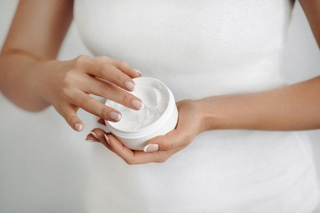 Mujer de primer plano sostiene y aplica crema protectora en las manos Cuidado de la piel de las manos Crema cosmética