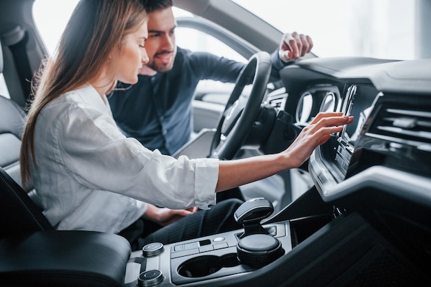 Mujer probando auto con la ayuda de un asistente masculino en el interior del salón.