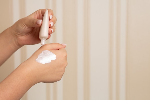 Mujer probando la base de maquillaje brillante crema en su mano. Espacio para texto