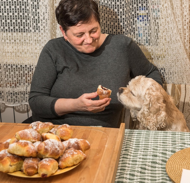 Mujer probando croissants recién horneados espolvoreados con azúcar glas en la cocina