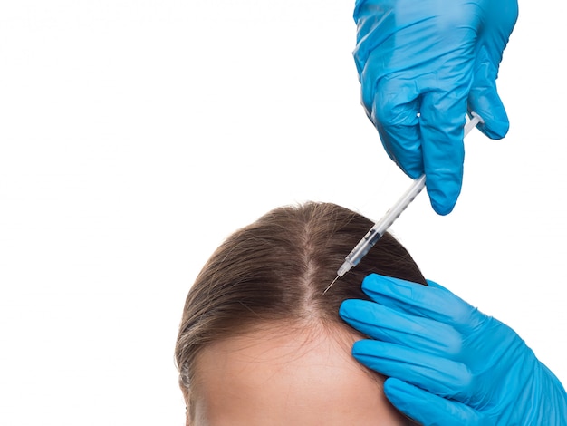 Foto mujer con problema de pérdida de cabello recibiendo inyección, vista de cerca. manos de un médico con jeringa.