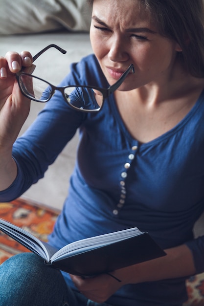 Una mujer con problemas de visión está leyendo un libro con gafas.