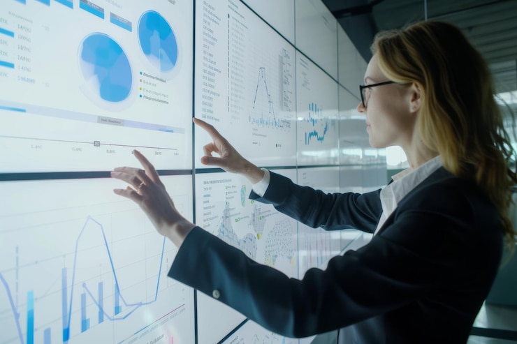 Foto una mujer profesional enfocada analiza múltiples visualizaciones de datos en una gran pantalla interactiva que integra información compleja en una oficina moderna