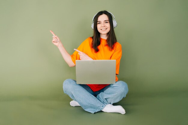 Mujer profesional joven que trabaja con confianza en una computadora portátil que apunta a un espacio vacío para texto y publicidad