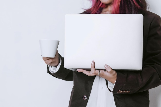Mujer profesional en traje sostiene una computadora portátil y una taza de café sobre fondo blanco con espacio de texto