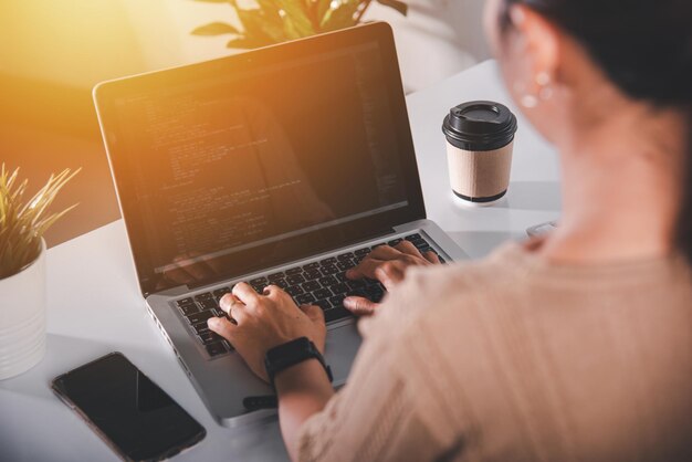 Mujer programadora escribiendo código de programa sentada en el lugar de trabajo en la oficina