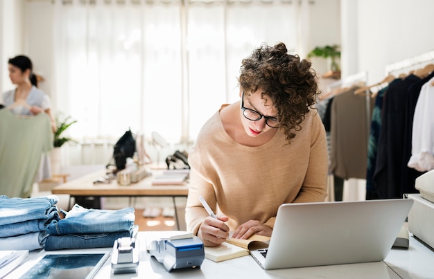 Una mujer propietaria de un negocio está usando la computadora portátil.