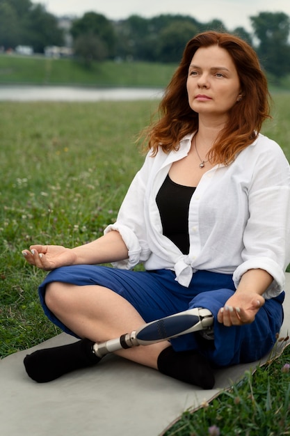 Foto mujer con prótesis de pierna haciendo yoga